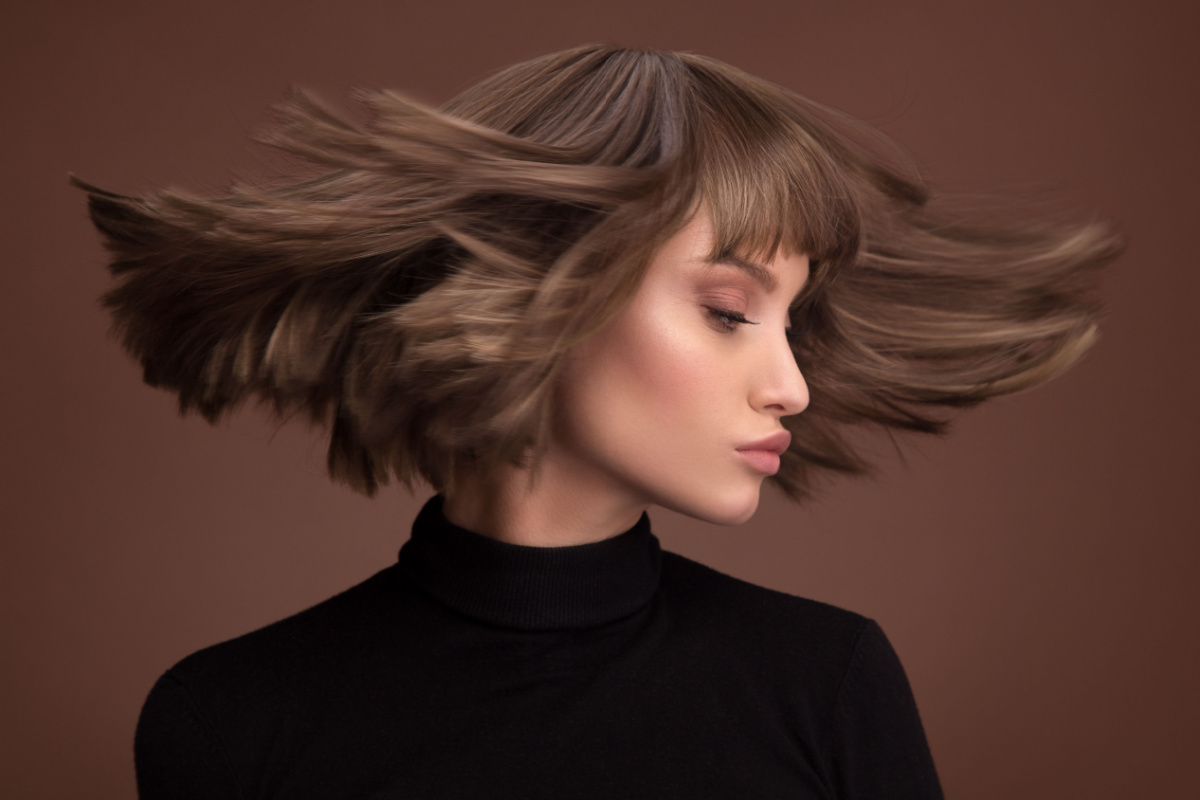 Mulher de cabelo castanho balançando o cabelo para o lado